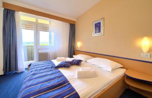 a hotel room with a large bed with a window at Hotel Dražica - Hotel Resort Dražica in Krk