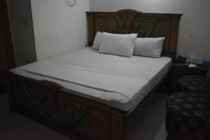 a bed with a wooden frame with two pillows on it at Hotel Basaira in Lahore