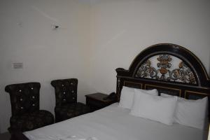 ラホールにあるHotel Basairaのベッドルーム1室(ベッド1台、椅子2脚付)