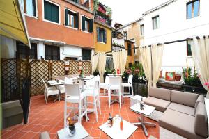 eine Terrasse mit weißen Stühlen und Tischen auf dem Balkon in der Unterkunft Hotel Fontana in Venedig