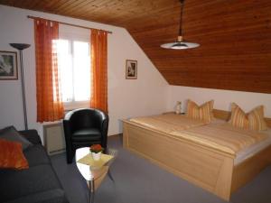 een slaapkamer met een bed, een stoel en een bank bij Ferien- und Obsthof Dillmann in Langenargen