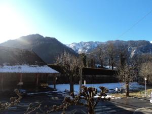 un edificio cubierto de nieve con montañas en el fondo en Les Tilleuls, en Le Biot