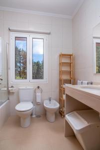 a white bathroom with a toilet and a sink at Valle Paraizo in Camacha