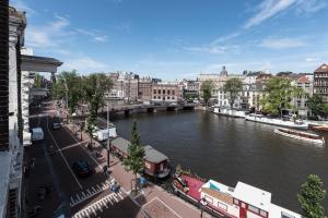 einen Fluss in einer Stadt mit einer Brücke und Gebäuden in der Unterkunft Hotel Amstelzicht in Amsterdam