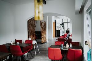 a dining room with tables and red chairs at RobrookS Hotel Garni in Hiddenhausen