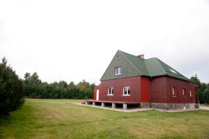 a red barn with a green roof in a field at Penzion Hájovna in Klíny