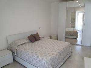 Habitación blanca con cama y espejo en Casa Mo Ma vacanze Ischia, en Isquia