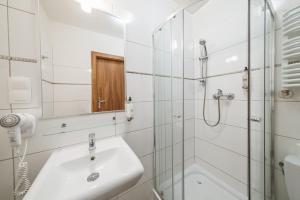 a white bathroom with a sink and a shower at Hotel Polonia Centrum in Wrocław