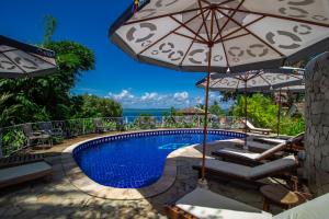 een zwembad met parasols en stoelen en de oceaan bij Pousada Natureza in Morro de São Paulo