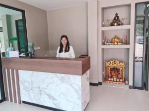 a woman sitting at a counter in a room at Grand Maihom Hotel in Chiang Mai