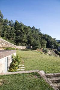 a large grassy field with a stone wall and stairs at Quinta da Casa Nova in Santo Tirso