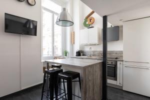a kitchen with white cabinets and a counter with stools at DIFY Boileau - Foch in Lyon