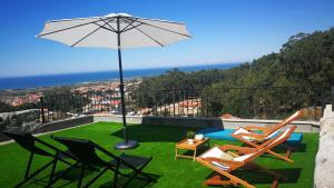 a patio with a table and chairs and an umbrella at Casa Colmeia in Esposende