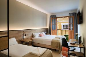 a hotel room with two beds and a window at Sweet Sevilla Suites in Seville