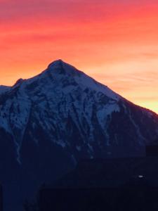einen schneebedeckten Berg mit Sonnenuntergang im Hintergrund in der Unterkunft Wohnung mit See und Bergsicht im vier Sterne Hotel in Beatenberg