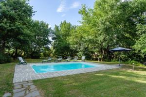una piscina con sillas y una sombrilla en un patio en Casa Ilenia, en Marciano Della Chiana