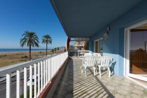 een balkon met witte stoelen en de oceaan bij Apartamento en 1era linea mar con terraza de 25m2 in Castelldefels