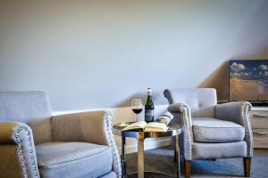 uma sala de estar com duas cadeiras e uma mesa com um copo de vinho em Landhaus Sylter Hahn em Westerland