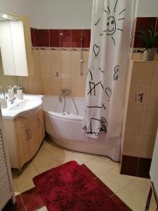 y baño con bañera, lavamanos y cortina de ducha. en JOE APARTMAN en Kőszeg