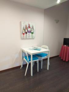 een witte tafel met twee stoelen en een schilderij aan de muur bij Serpa's Apartments in Porto