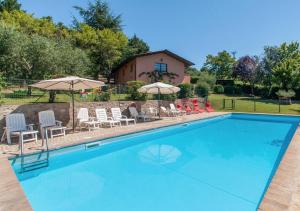 a swimming pool with chairs and umbrellas in front of a house at Agriturismo Il Poggio, Casa Rosa in Umbertide