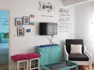 ヒホンにあるApartamento Playa San Lorenzoのテレビ、椅子、テーブルが備わる客室です。