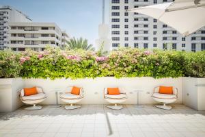 una fila de sillas con almohadas naranjas en el patio en Berkeley Shore Hotel en Miami Beach