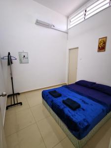 a bedroom with a blue bed in a white room at SinggahSini Homestay Balok / Gebeng in Kuantan