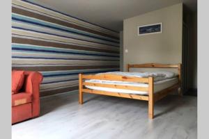 um quarto com uma cama de madeira e uma cadeira vermelha em LES HAUTEURS DE TRESTRAOU em Perros-Guirec