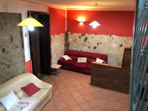 sala de estar con sofá rojo y pared de piedra en villa aurora, en Francavilla di Sicilia