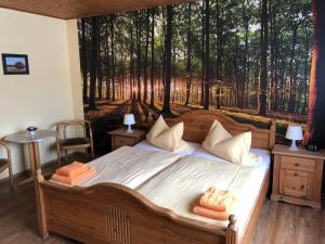 ein Schlafzimmer mit einem Bett mit einem Gemälde eines Waldes in der Unterkunft Hotel Schützenhaus in Brück