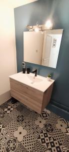 een badkamer met een wastafel en een spiegel bij Le Clipper in Saint-Pierre