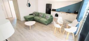 a living room with a green couch and white chairs at Le Clipper in Saint-Pierre