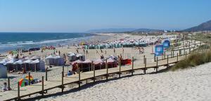 a beach with many umbrellas and crowds of people at EvaJoe in Esposende