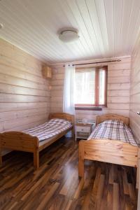 two beds in a room with wooden walls at Kultala Cottage in Korkeakoski