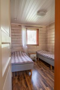 two beds in a room with wooden walls and a window at Kultala Cottage in Korkeakoski