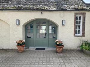 uma porta verde de uma casa com dois vasos de flores em Barns Library em Peebles