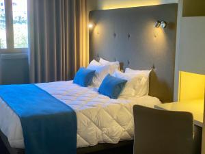 a bedroom with a large bed with blue pillows at Vilar Oporto Hotel in Porto
