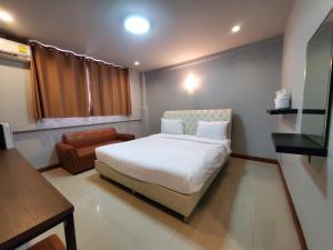 um quarto com uma cama branca e uma cadeira em Keeree Boutique Hotel em Phetchaburi