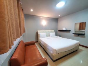 a bedroom with a bed and a leather couch at Keeree Boutique Hotel in Phetchaburi