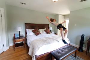 una joven saltando sobre una cama en Clay Corner Inn, en Blacksburg