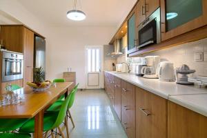 a large kitchen with a table and green chairs at Mantarini House in Áyios Andónios +16 photos
