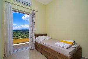 Schlafzimmer mit einem Bett und einem Fenster mit Aussicht in der Unterkunft Mantarini House in Áyios Andónios