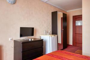 a room with a refrigerator and a tv and a bedroom at WaterLoo Hotel in Loo