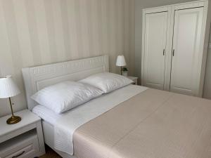 - une chambre avec un lit blanc et un couvre-lit blanc dans l'établissement Apartament Bliżej Morza, à Kołobrzeg