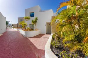 ein weißes Haus mit Palmen und Bürgersteig in der Unterkunft Villa Caterina, Luxury Villa with Heated Pool Ocean View in Adeje, Tenerife in Adeje