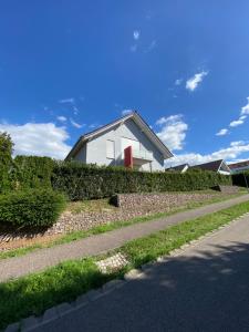 a white house on a hill next to a street at Ferienwohnung Müller in Lahr