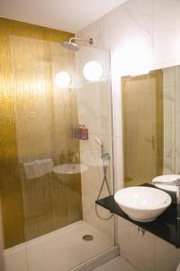a bathroom with a glass shower and a sink at Hôtel Le Versailles in Versailles