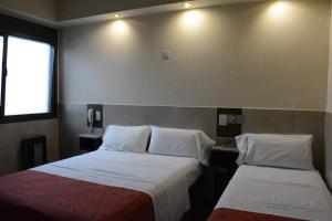 um quarto de hotel com duas camas e uma janela em Hotel Santa Cruz em Buenos Aires