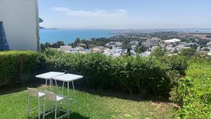 two white tables and chairs sitting on top of a hill at La Villa Des Oliviers in Sidi Bou Saïd +3 photos